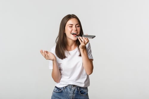 friendly-attractive-brunette-girl-talking-on-speaker-record-voice-message-at-smartphone-white-1